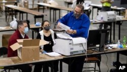 FILE - Election workers scan ballots during a recount of the presidential vote, at the Georgia World Congress Center, in Atlanta, Georgia, Nov. 25, 2020.