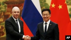 资料照：2019年11月26日，在北京人民大会堂举行的签字仪式前，俄罗斯第一副总理兼财政部长西卢安诺夫(左)与现任中国国家副主席韩正握手。（美联社）