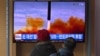 People watch a television screen showing a news broadcast with file footage of a North Korean missile test, at a railway station in Seoul, South Korea, on March 5, 2022.