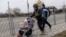 A service member of the Ukrainian armed forces helps to evacuate a child from the town of Irpin, on the only escape route used by locals after days of heavy shelling, while Russian troops advance towards the capital, in Irpin, near Kyiv, Ukraine, March 7, 2022.