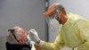 A health worker takes a swab sample from a man to test for the coronavirus disease, at the Fiumicino Airport in Rome, Italy, Sept. 23, 2020.