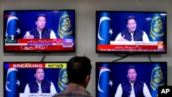 A man watches news channels broadcast a live address to the nation by Pakistan's Prime Minister Imran Khan, in Islamabad, Pakistan, March 31, 2022. 