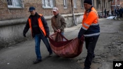 2022年3月23日，在乌克兰基辅，邻居们从被炮击的公寓里搬出被打碎的窗户玻璃碎片。（美联社）