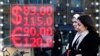 FILE - People walk past a currency exchange office screen displaying the exchange rates of U.S. dollar and euro to Russian rubles in Moscow's downtown, Russia, Feb. 28, 2022. 