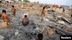 2016年5月3日，在缅甸西部实兑附近的诺开邦，大火摧毁了流离失所的罗欣亚穆斯林的临时住所，一群男童正在烧毁的住房废墟中寻找有用物品。