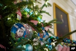 Ornaments containing self-portraits of students from across the country hang from a tree in the State Dining Room of the White House during a press preview of holiday decorations at the White House, Monday, Nov. 28, 2022, in Washington. (AP Photo/Patrick Semansky)