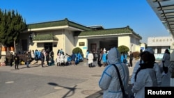 人们身穿防护服站在上海的一家火葬场外。（2022年12月24日）