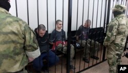 ពលរដ្ឋអង់គ្លេសពីរនាក់ លោក Aiden Aslin (ឆ្វេង) និង លោក Shaun Pinner (ស្តាំ) និងជនជាតិម៉ារ៉ុក លោក Saaudun Brahim (កណ្តាល) អង្គុយនៅក្នុងបន្ទប់សវនាការក្នុងទីក្រុង Donetsk ក្នុងទឹកដីដែលស្ថិតនៅក្រោមការគ្រប់គ្រងរបស់រដ្ឋាភិបាលនៃសាធារណរដ្ឋប្រជាមានិត Donetsk ភាគខាងកើតអ៊ុយក្រែនកាលពីថ្ងៃព្រហស្បតិ៍ ថ្ងៃទី៩ ខែមិថុនា ឆ្នាំ២០២២។