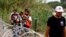 Migrants walk past razor wire fencing to be taken by the Border Patrol after crossing the Rio Grande river towards the U.S. in Eagle Pass, Texas, May 22, 2022. 