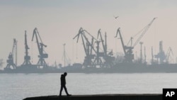 Архів. Чоловік гуляє з портовими кранами на задньому плані в торговому порту Маріуполя, Україна, 23 лютого 2022 р. (Фото AP/Сергій Гриць, файл)