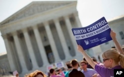 FILE – A demonstrator holds a sign outside the Supreme Court in Washington, D.C., June 30, 2014.