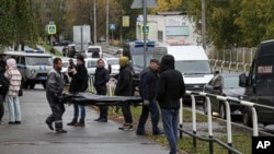 2022年9月26日，在俄罗斯伊热夫斯克市第88学校发生枪击事件的现场，殡仪人员抬着一具遇难者遗体。