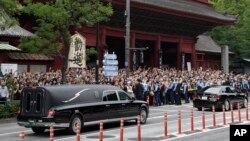 日本前首相安倍晋三的葬礼举行后，运载安倍棺木的灵车离开寺庙，日本民众路旁送行。（2022年7月12日）
