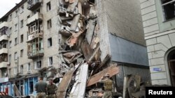 Ukrajinski vojnici ispred pogođene stambene zgrade u Harkovu, 11. jul 2022.