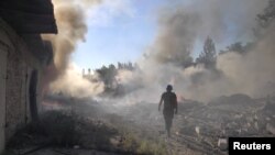 乌克兰一名救援人员在顿涅茨克地区托列茨克镇被俄军炸毁的住宅区废墟中行走。（2022年7月27 日）