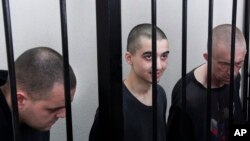 Двоє громадян Великої Британії Ейден Аслін і Шон Піннер і марокканець Саудун Брагім за ґратами в залі суду в Донецьку, на території, що підконтрольна уряду Донецької Народної Республіки, на сході України, четвер, 9 червня 2022 р. (AP Photo)