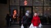 FILE - Two women walk past a currency exchange office screen displaying the exchange rates of U.S. dollar and euro to Russian rubles in Moscow, Russia, April 1, 2022.