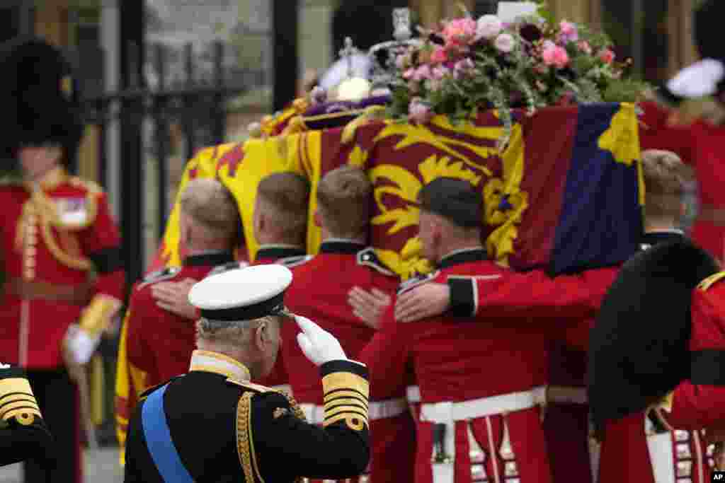 King Charles III salutes as the coffin of his mother Queen Elizabeth II is carried into Westminster Abbey for her funeral in central London, Sept. 19, 2022. 