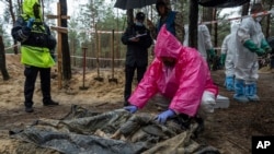 一名专家在乌克兰伊久姆对一名被发现的平民尸体进行检查（2022年9月24日）