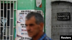 Seorang pria berjalan melewati sejumlah poster di dinding yang bertuliskan "Tidak ada kata menyerah. Identitas Serbia tetap ada" di wilayah Mitrovica Utara, Kosovo, pada 1 September 2022. (Foto: Reuters/Ognen Teofilovski)
