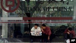 In this undated file photo, men in Guangzhou, southeastern Guangdong province, share a newspaper outside a branch of the state-run Bank of China, which recently halted business with North Korea's Foreign Trade Bank, in the latest sign of Beijing-Pyongyang tensions.