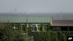 FILE - A man walks on a pedestrian crossing point near the Dnipro river and Zaporizhzhya nuclear plant on the other side in Nikopol, Ukraine, Aug, 22, 2022.