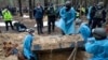 Emergency workers move a body during the exhumation in the recently retaken area of Izium, Ukraine, Sept. 16, 2022. Ukrainian authorities discovered a mass burial site near the recaptured city.