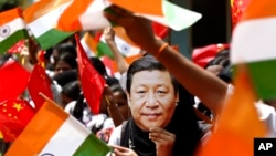 FILE- An Indian schoolgirl wears a mask of Chinese President Xi Jinping to welcome him on the eve of his visit in Chennai, India, Oct. 10, 2019. 