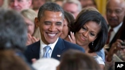 FILE - President Barack Obama and first lady Michelle Obama applaud during the portrait unveiling ceremony for former President George W. Bush and former first lady Laura Bush portraits, May 31, 2012, at the White House in Washington. 