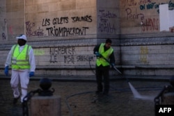 Trabajadores limpian el Arco del Triunfo un día después de una protesta de chalecos amarillos contra el alza de combustibles y el costo de vida. Diciembre. 2, 2018 in Paris. El grafiti en el monumento dice "Los chalecos amarillos triunfarán".