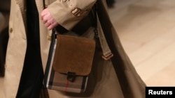 بارانی کمر دار و طرح چهارخانه روی کیف از نشانه های معروف مارک بربری است.