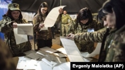 UKRAINE – Ukrainian government soldiers, members of the local election commission count ballots in a tent used as a polling station during the presidential elections in Mariinka, near a contact line not far from Donetsk, 31, 2019