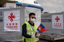 បុគ្គលិកប្រចាំអកាសយានដ្ឋានអន្តរជាតិភ្នំពេញម្នាក់កាន់ទង់ជាតិកម្ពុជា និងចិន ខណៈយន្តហោះដឹកក្រុមគ្រូពេទ្យចិន និងសម្ភារៈបរិក្ខាពេទ្យពីប្រទេសចិន បានមកដល់កម្ពុជា ដើម្បីជួយកម្ពុជាក្នុងការប្រយុទ្ធនឹងការឆ្លងរាលដាលនៃវីរុសកូរ៉ូណា ឬកូវីដ១៩ នៅរាជធានីភ្នំពេញ ថ្ងៃទី២៣ ខែមីនា ឆ្នាំ២០២០។