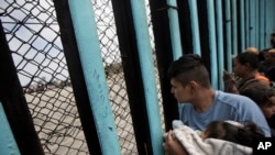 Grupa ljudi kod zida podignutog kod Tijuane na meksičko-američkoj granici