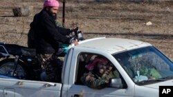 A group of unidentified militants drive near Syria's Quneitra border crossing between Syria and the Israeli-controlled Golan Heights, seen from the Israeli-controlled Golan Heights, Nov. 28, 2016. Israeli aircraft struck a machine gun-mounted vehicle inside Syria Nov. 27, killing four IS-affiliated militants inside after they had opened fire on a military patrol on the Israeli side of the Golan Heights, the Israeli military said.