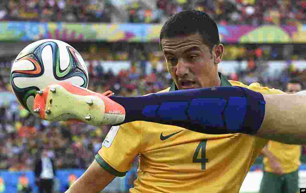 Australia&#39;s Tim Cahill, left, watches as Netherlands&#39; Ron Vlaar clears the ball during the group B World Cup soccer match between Australia and the Netherlands at the Estadio Beira-Rio in Porto Alegre, Brazil.