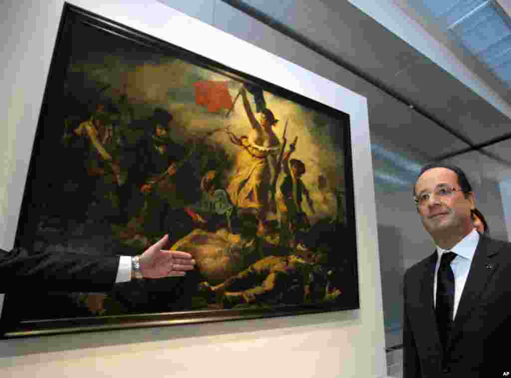 2012年12月4日，法国总统奥朗德站在卢浮宫里的名画《自由引导人民》旁边。