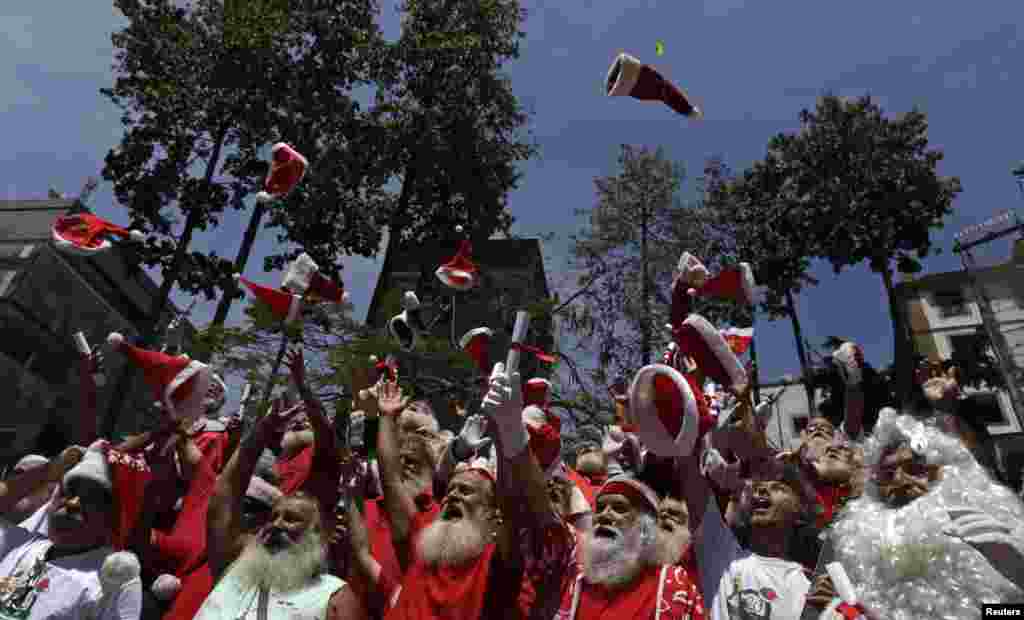 Para siswa dari sekolah Santa Claus, Brazil melemparkan topi mereka ke udara selama upacara wisuda di kota Rio de Janeiro.