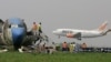A passenger plane lands as workers dismantle an abandoned aircraft at Murtala Muhammed International Airport in Lagos, Nigeria, January 31, 2013. Nigerian aviation officials have begun trying to dismantle and remove the hulks of abandoned airplanes from 