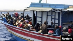FILE - Illegal migrants who attempted to sail to Europe sit in a boat carrying them back to Libya, after their boat was intercepted at sea by the Libyan coast guard, at Khoms, Libya, May 6, 2015. 