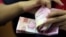 Seorang karyawan tengah menghitung lembaran uang kertas rupiah di sebuah tempat penukaran uang di Jakarta, 23 Oktober 2018. (REUTERS/Beawiharta). 