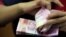 Seorang karyawan tempat penukaran mata uang menghitung uang kertas rupiah, Jakarta, 23 Oktober 2018. (Foto: Reuters)
