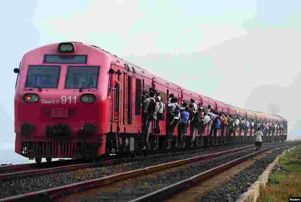Sri Lankans hold on to the sides of a passenger train in Colombo.