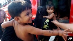Rohingya minority children held by women board a bus after they were rescued by Thai authorities in Songkhla province, southern Thailand, Jan. 11, 2013.