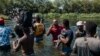 FILE - Migrants wade through the Rio Grande as they move from Ciudad Acuña, Mexico, into Del Rio, Texas, Sept. 19, 2021. 
