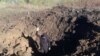 A police officer stands on a bottom of a shell crater left by a Russian military strike at a compound of the Pivdennoukrainsk Nuclear Power Plant, amid Russia's invasion of Ukraine, in Yuzhnoukrainsk, Mykolaiv region, Ukraine, in this handout picture rele