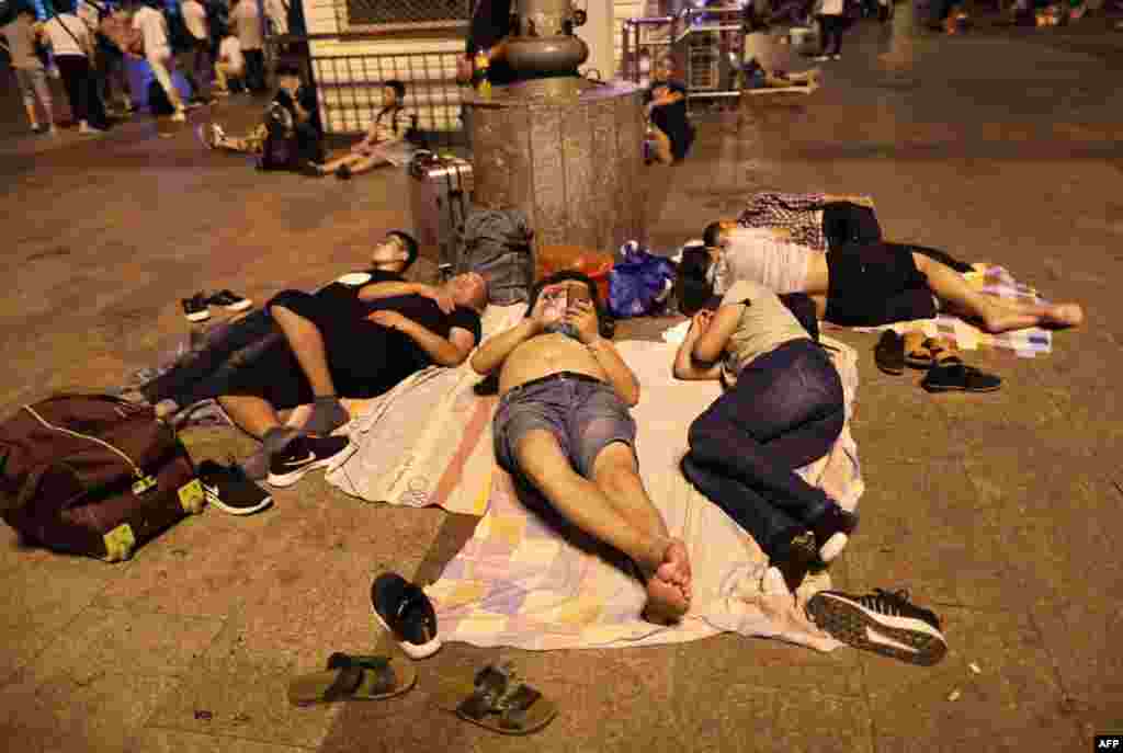 2018年8月17日，人们在北京火车站外的广场等火车时，在地上睡觉。