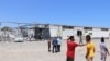 FILE - After the bombing of the detention center that killed more than 50 civilians and wounded more than 130, migrants watch authorities search for human remains, near Tripoli, Libya, July 3, 2019. (H. Murdock/VOA)