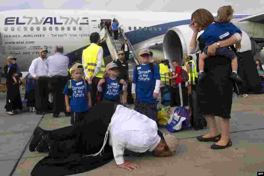 Seorang imigran Yahudi yang bersama keluarganya baru tiba dari Amerika &#39;sujud syukur&#39; dengan mencium landasan saat kedatangan mereka di Bandara Internasional Ben Gurion dekat Tel Aviv, Israel.