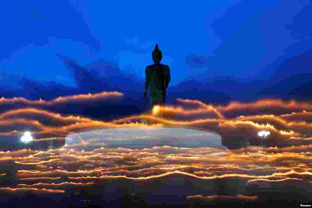 Warga Budha menyalakan lilin sambil mengelilingi patung Buddha raksasa &nbsp;pada festival Hari Asanha Puja, di candi Nakhon Pathom, pinggiran Bangkok, Thailand.